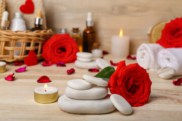 Fototapeta na wymiar Spa stones with rose and candle on wooden table, closeup. Valentine's Day celebration