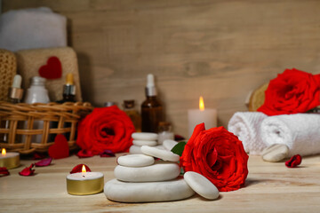 Spa stones with rose and candle on wooden table, closeup. Valentine's Day celebration