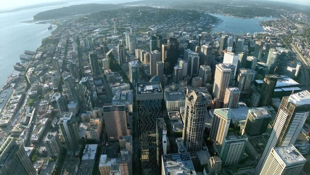 High up drone shot of Seattle's downtown skyscrapers surrounded by the Puget Sound and Lake Union.