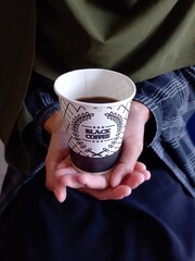 Beautiful woman in hijab holding a disposable cup of coffee.