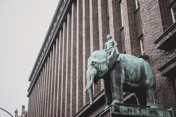 Statue of a man sitting on elephant by dark brick building in Hamburg, Germany