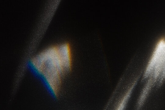 Rainbow light effect from sun flares on black background, colorful glare and shine, light rays on sparkling surface. Rainbow refraction of sunlight. Natural light effects, iridescent colors