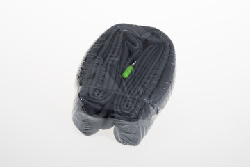 Top view of bicycle inner tube held by elastic in plastic packaging on white background