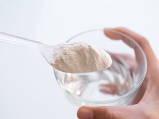 Banan Raw Powder,Banana Flour on Spoon with Water in Glass,Finger Make Flour Banana in Glass on white Background,Traditional Herb in Asian Thailand,Vegetable Food  nature for Diet and Treat Gastritis.