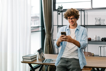 Young businessman using smartphone app texting in workplace for business work