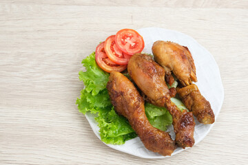 Grilled Chicken or Ayam Bakar with herbs and spices. Served on a plate with lettuce and tomatoes.
