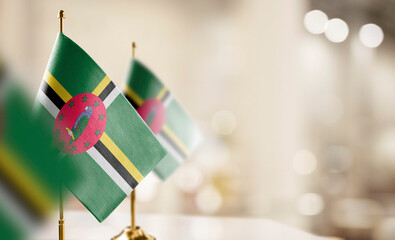 Small flags of the Dominica on an abstract blurry background