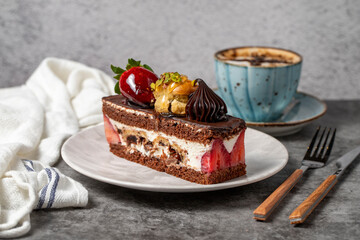 Strawberry and chocolate cake on a dark background. Slice of layered chocolate cake with coffee cup. Bakery cake products. close up