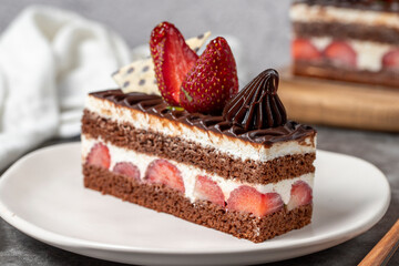 Strawberry and chocolate cake on a dark background. Slice of layered chocolate cake. Bakery cake products. close up