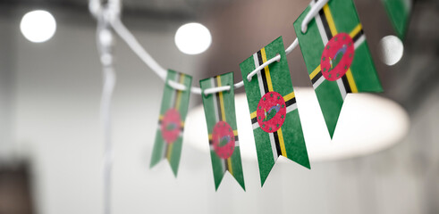 A garland of Dominica national flags on an abstract blurred background