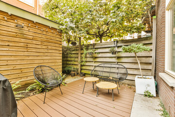 a backyard area with two chairs and a table on the deck, surrounded by a wooden fence that's made...
