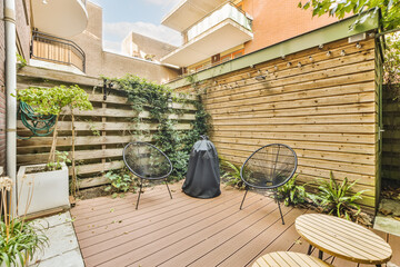 a backyard area with wooden decking and plants on the wall, two chairs and a table in the corner