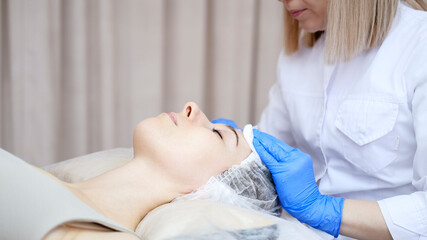 The cosmetologist dries the client's face in the beauty spa salon.