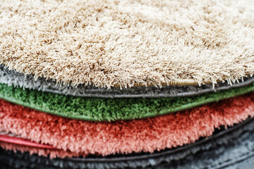 A stack of round-shaped carpets made of synthetic material. Sale of floor coverings in a chain store. Close-up