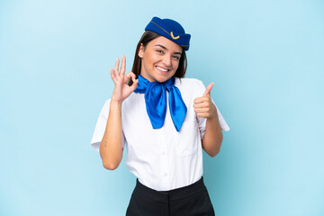 Airplane stewardess caucasian woman isolated on blue background showing ok sign and thumb up gesture