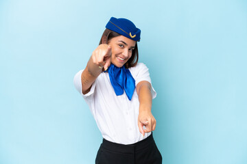 Airplane stewardess caucasian woman isolated on blue background points finger at you while smiling