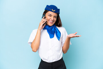 Airplane stewardess caucasian woman isolated on blue background keeping a conversation with the mobile phone with someone