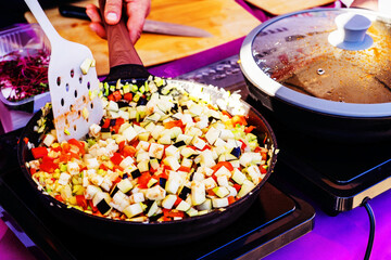 Finely chopped vegetables are fried in a steel pan, stirring with a spatula during cooking. selective focus closeup
