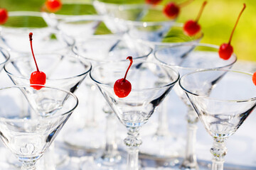 Obraz premium Cocktail glasses decorated with cherries. Preparation of alcoholic beverages at a party or holiday. selective focus