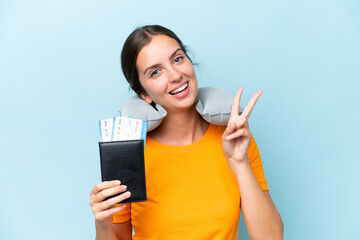 Young beautiful woman with Inflatable travel Pillow isolated on blue background smiling and showing victory sign