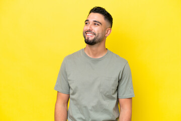 Young Arab handsome man isolated on yellow background thinking an idea while looking up
