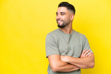 Young Arab handsome man isolated on yellow background looking to the side and smiling