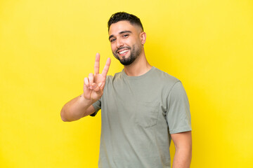 Young Arab handsome man isolated on yellow background smiling and showing victory sign