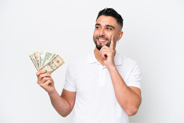 Young Arab man taking a lot of money isolated on white background thinking an idea while looking up