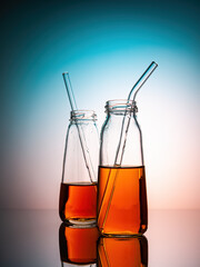 Apple juice in transparent bottles with glass tubes with blue light. Studio shot. Advertising photo. Creative project. Bright, vived.