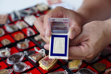 Closeup hand holds Thai Buddha amulet from amulet collection. Concept, faith and belief for...