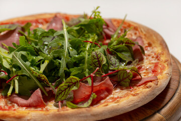 pizza with ham and basil on desk on white background