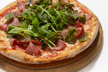 pizza with ham and basil on desk on white background