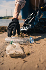 Earth day female activist puts a plastic bottle in a garbage bag. closeup