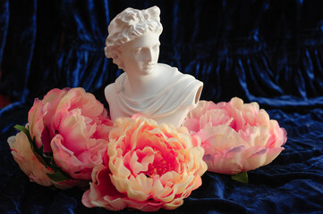 Pearl necklace on the statue of Apollo in flowers on a dark background. copy space