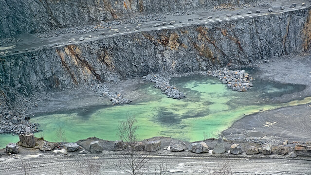 Steps on the slope of a porphry quarry with grey and brown stone and green puddles in Lessines, Wallonia, Belgium 