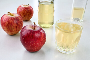 Apple cider vinegar in a glass cup with apples in the background.