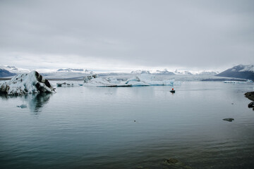 A boat with sails through the Jökulsárlón glacier lagoon in Iceland past icebergs that have broken away from the glacier tongue Breiðamerkurjökull. With a view of Hvannadalshnúkur.