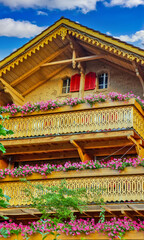 Obraz premium Old wooden house with flowers on the balcony in Swiss Alps