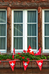 Old traditional wooden window with Swiss flags