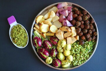 Mixed cut and marinated vegetables for Undhiyu. stuffed brinjals, fried potatoes, sweet potatoes, purple yam. preparation for surti undhiyu Indian Gujarati dish. Makar Sankranti Special Dish.
