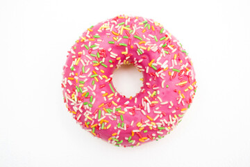 Pink donut decorated with colorful sprinkles isolated on white background.