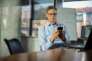 Businessman in office. Handsome man using the phone at work