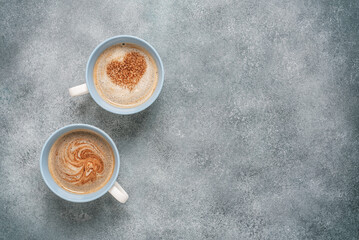 Cup of coffee with a heart on a gray background. Valentine's Day. Two mugs of coffee. Top view.