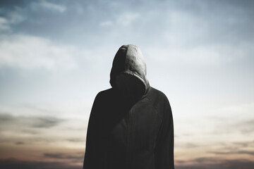surreal man with hood and obscured face wanders aimlessly - obrazy, fototapety, plakaty