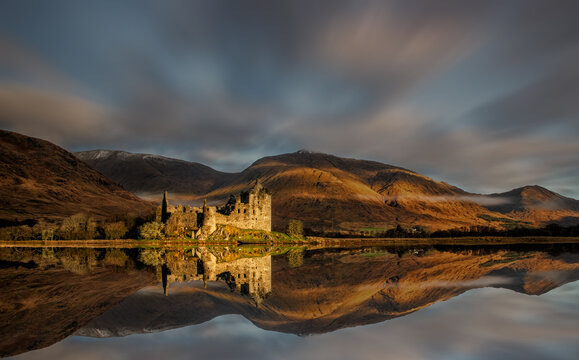 Scottish Castle, Kilchurn Castle, Loch Awe near Oban in the Scottish Highlands. Historic castle reflected in the loch with mountain backdrop. Dramatic lighting on the castle and mountains.