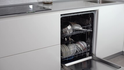 Open dishwasher with clean utensils in it.