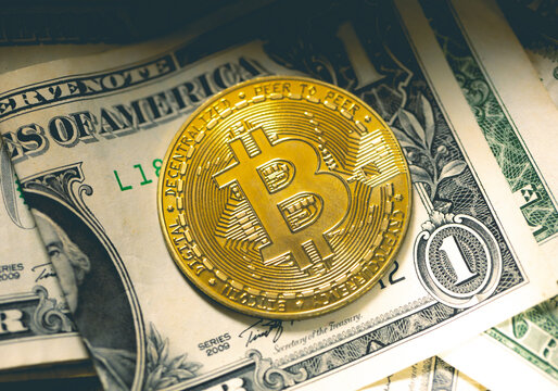 Bitcoin - BTC.  Uma moeda de Bitcoins sobre cédulas de dólares americanos dentro de uma caixa de dinheiro em fotografia macro. Conceitos de criptomoedas, finanças e risco.	