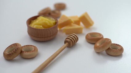 honey in a wooden bowl, bagels and cheese on a white background