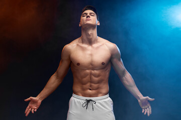 Fototapeta na wymiar Athlete man with beautiful torso isolated on black background with coloured fume