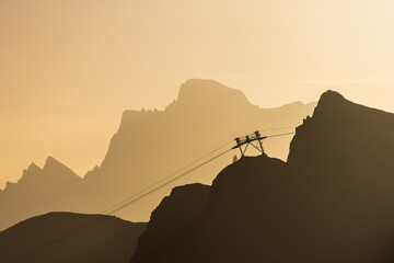 Silhouette of a gondola cableway up to a mountain during sunrise with the first sunbeams of the day...